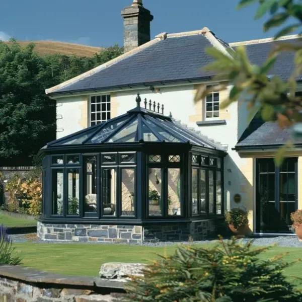 Black framed conservatory with a glass roof beside a lawn