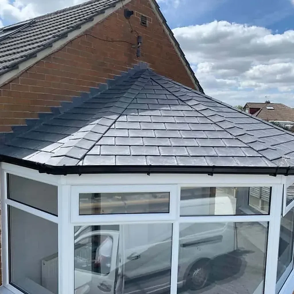 Grey tiled roof on a white framed conservatory attached to a brick house